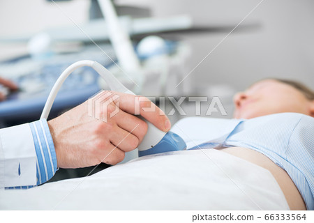 Doctors hand moving transducer on woman belly 66333564
