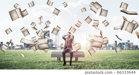 Many old books falling from above and student guy sitting on bench Many old books falling from above and student guy sitting on bench 66333644