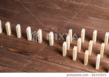 Rows of dominoes standing on wooden table 66333833