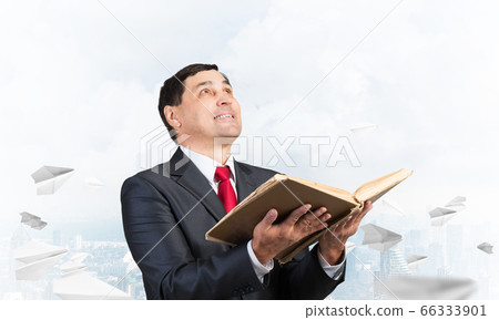 Happy businessman holding open old book Happy businessman holding open old book 66333901
