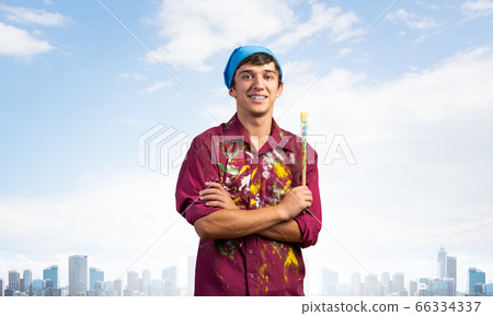 Smiling young painter artist holding paintbrush 66334337