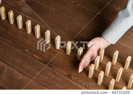 Businesswoman protecting dominoes from falling 66335089