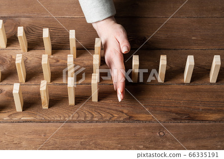 Businesswoman protecting dominoes from falling Businesswoman protecting dominoes from falling 66335191