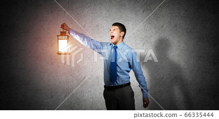 Horrified businessman holding glowing lantern 66335444
