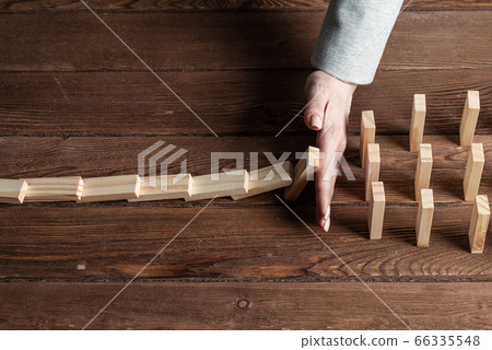 Businesswoman protecting dominoes from falling 66335548