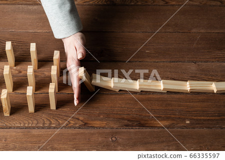 Businesswoman protecting dominoes from falling 66335597