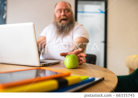 Bald bearded man in white tshirt stretching his hand to the apple 66335745