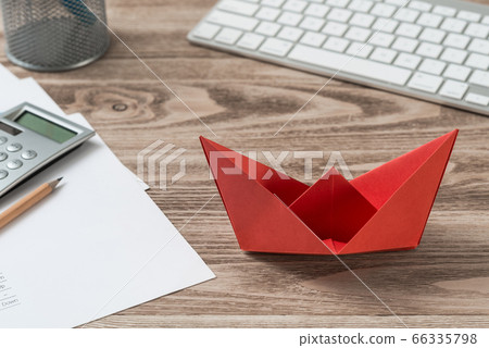 Businessman workspace at desk with red paper ship 66335798