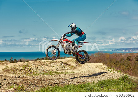 Extreme concept, challenge yourself. Extreme jump on a motorcycle on a background of blue sky with clouds. Copy space, all or nothing. 66336602