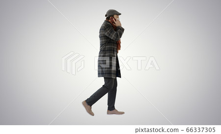 Adult man wears protective medical mask talking on the phone and walking on gradient background. 66337305