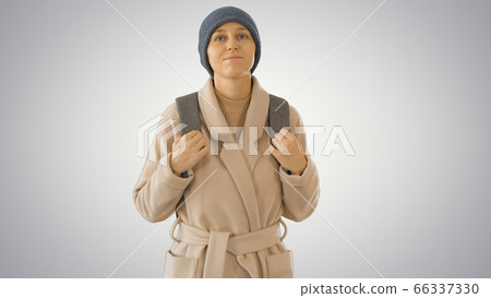 Young woman wearing coat and backpack walking on gradient background. Young woman wearing coat and backpack walking on gradient background. 66337330