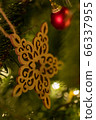 A wooden star shaped Christmas Tree Decoration hanging from a tree 66337955