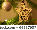 A wooden star shaped Christmas Tree Decoration hanging from a tree 66337957