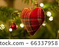A fabric heart shaped Christmas Tree Decoration hanging from a tree 66337958