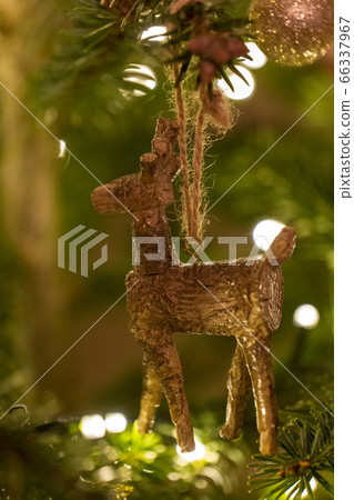 A wooden reindeer shaped Christmas Tree Decoration hanging from a tree A wooden reindeer shaped Christmas Tree Decoration hanging from a tree 66337967
