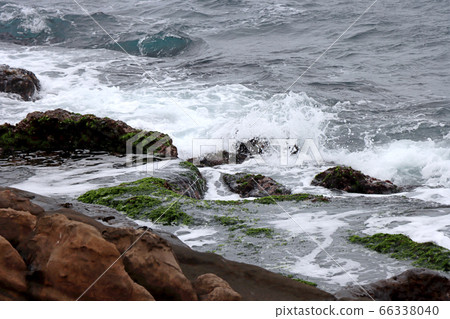 The waves are beating against the rocky shore 66338040