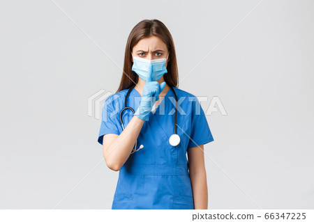 Covid-19, preventing virus, health, healthcare workers and quarantine concept. Angry female nurse in blue scrubs, medical mask, warning keep voice down, tell to be quiet, shushing at camera 66347225