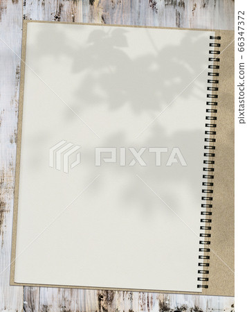 A sketchbook placed on a white wooden bench and the shadows of the leaves can be seen. A sketchbook placed on a white wooden bench and the shadows of the leaves can be seen. 66347372