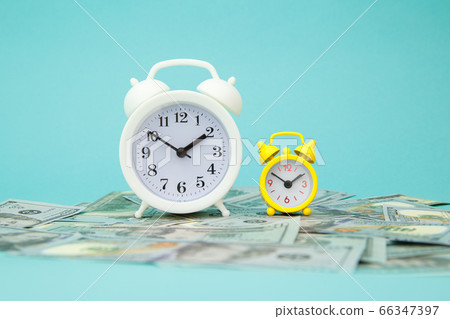 Close-up of alarm clock and money on blue background. Business Finance and Money concept. Save money for prepare in the future. Time is money concept Close-up of alarm clock and money on blue background. Business Finance and Money concept. Save money for prepare in the future. Time is money concept 66347397