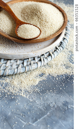 Raw uncooked fonio seeds with a spoon on a plate 66351528