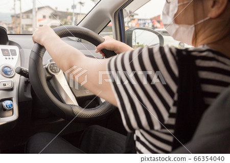 Driving young woman wearing a mask Driving young woman wearing a mask 66354040