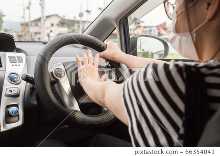 Driving young woman wearing a mask Driving young woman wearing a mask 66354041