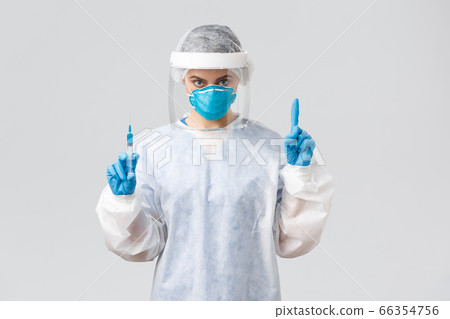 Covid-19, medical research, diagnosis, healthcare workers and quarantine concept. Determined doctor in PPE costume, personal protective equipment, hold syringe with coronavirus vaccine for patient Covid-19, medical research, diagnosis, healthcare workers and quarantine concept. Determined doctor in PPE costume, personal protective equipment, hold syringe with coronavirus vaccine for patient 66354756