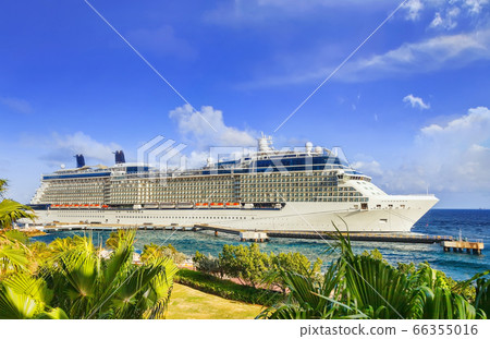 Cruise ship docked at tropical island on sunny day 66355016