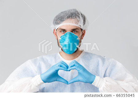 Covid-19, pandemic, healthcare workers fighting virus outbreak. Doctor in personal protective equipment, medical respirator and rubber gloves, showing heart sign, stay strong during coronavirus 66355045