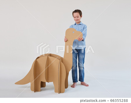Little dreamer boy playing with a cardboard dinosaur Brontosaurus. Childhood. Fantasy, imagination. Little dreamer boy playing with a cardboard dinosaur Brontosaurus. Childhood. Fantasy, imagination. 66355288