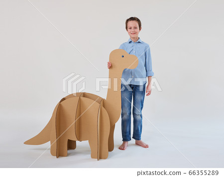Little dreamer boy playing with a cardboard dinosaur Brontosaurus. Childhood. Fantasy, imagination. 66355289