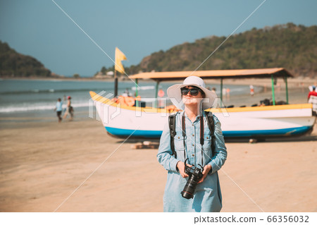Canacona, Goa, India. Young Caucasian Lady Woman With Camera Standing On Famous Palolem Beach Near Arabian Sea In Summer Sunny Day 66356032