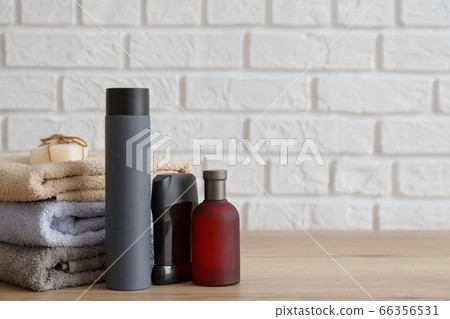 Stack of towels and man toiletries on wooden table. 66356531