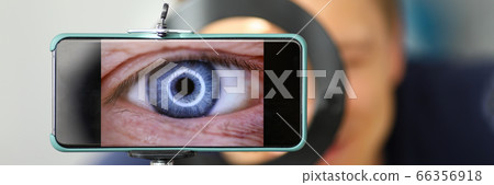 Man making video trying to shoot his own eye using modern smartphone camera 66356918