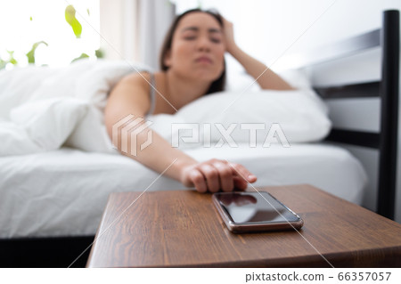 Sleepy young woman waking up of incoming call 66357057