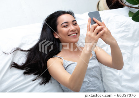 Young woman enjoying using cell phone at home Young woman enjoying using cell phone at home 66357070