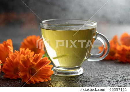 A cup of calendula tea with fresh calendula 66357111