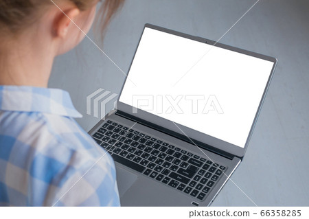 Woman looking at grey laptop with white blank screen Woman looking at grey laptop with white blank screen 66358285