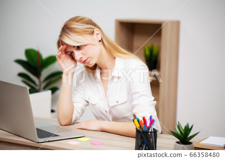 Tired young businesswoman exhausted at workplace in her office 66358480
