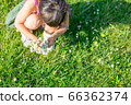 Girl playing with nature to collect white clover and make a bouquet 66362374