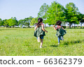 Children running on a cloudless blue sky and fresh green grass 66362379