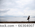 Silhouette of a boy flying a toy plane on the sandy beach 66364007