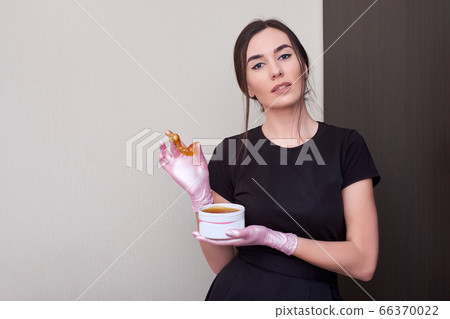 Cosmetologist hands are holding liquid sugar paste or wax . Copy space. Cosmetologist hands are holding liquid sugar paste or wax . Copy space. 66370022