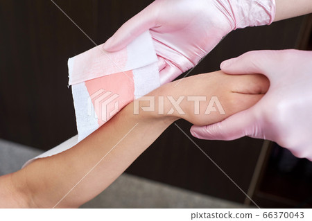 Beautician removes hair from womans hands with wax at home. Beautician removes hair from womans hands with wax at home. 66370043