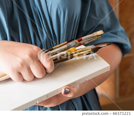 A woman holds brushes in her hands for drawing with watercolors. Hobby art concept. Close-up selective focus. 66371221