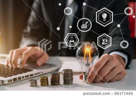 businessman hand holding lightbulb with using laptop computer and money stack in office. idea saving energy and accounting finance concept in office. businessman hand holding lightbulb with using laptop computer and money stack in office. idea saving energy and accounting finance concept in office. 66371489