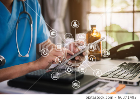 The doctor is working on a tablet and audio player and a digital tablet computer in a modern office in the morning at the desk. The doctor is working on a tablet and audio player and a digital tablet computer in a modern office in the morning at the desk. 66371492