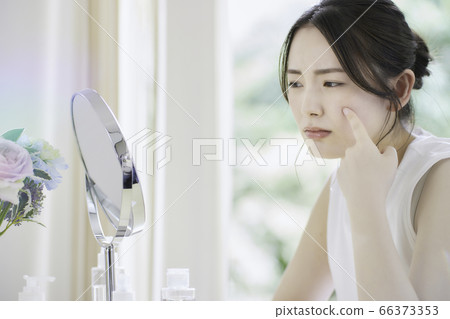 一名年輕女子在客廳裡照顧她的皮膚[擔心] 66373353