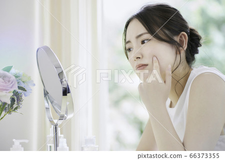 一名年輕女子在客廳裡照顧她的皮膚[擔心] 66373355