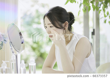 一名年輕女子在客廳裡照顧她的皮膚[擔心] 66373357